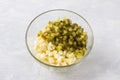 Glass bowl with diced apples and salted cucumbers on a light gray background. Cooking delicious homemade food step by