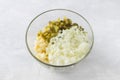 Glass bowl with diced apples, salted cucumbers and onion on a light gray background. Cooking delicious homemade food