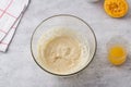 Glass bowl with egg-butter mixture, freshly squeezed orange juice on a gray background. Cooking greek easter orange