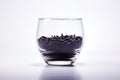 A glass bowl filled with black grains of wild rice on a white background. Can be used for food or health-related content