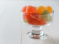 Glass bowl filled with colorful marmalade on a white wooden table Royalty Free Stock Photo