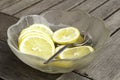 A glass bowl filled with lemon wedges stands on a wooden table. With the spoon, the slices are placed in refreshing water Royalty Free Stock Photo