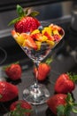 Glass bowl with fresh fruits salad on dark background. Bowl of fruit salad with berries and mango Royalty Free Stock Photo