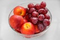 Glass bowl with fresh grapes and nectarines on white table, closeup Royalty Free Stock Photo