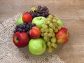 A glass bowl of fresh organic autumn fruit on crochet table cloth and oak wood table background.