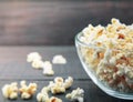 Glass bowl with freshly popped popcorn with salt on dark wooden