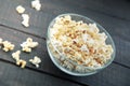 Glass bowl with freshly popped popcorn with salt on dark wooden