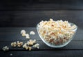 Glass bowl with freshly popped popcorn with salt on dark wooden