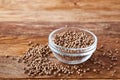 Glass bowl full of coriander seeds on rustic wooden background, close-up, side view, selective focus. Royalty Free Stock Photo