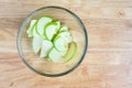 Glass bowl full of granny smith apple slices on a butcher block table, ready for baking Royalty Free Stock Photo