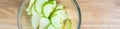 Glass bowl full of granny smith apple slices on a butcher block table, ready for baking Royalty Free Stock Photo