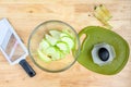 Glass bowl full of granny smith apple slices, mandolin slicer and cutting board on a butcher block table Royalty Free Stock Photo