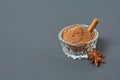 Glass bowl full of powder with cinnamon stick near star of anise lies on dark scratched desk on kitchen Royalty Free Stock Photo