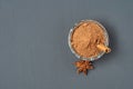 Glass bowl full of powder with cinnamon stick near star of anise lies on dark scratched desk on kitchen Royalty Free Stock Photo