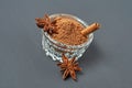 Glass bowl full of powder with cinnamon stick near star of anise lies on dark scratched desk on kitchen Royalty Free Stock Photo