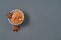 Glass bowl full of powder with cinnamon stick near star of anise lies on dark scratched desk on kitchen Royalty Free Stock Photo