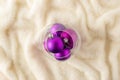 Glass bowl full of purple holiday decoration balls isolated on white fur with copy space. Flat lay Royalty Free Stock Photo