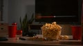 A glass bowl full of tasty popcorn, cups and remote control on table in living room. Family vacation, recreation Royalty Free Stock Photo