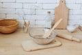 Glass bowl with groats and various kitchen utensils and dishware on wooden table