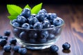Glass bowl holds fresh, organic blueberries on a wooden background