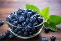 Glass bowl holds fresh, organic blueberries on a wooden background