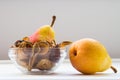 Glass bowl with homemade dried organic pear slices with fresh pears on white background