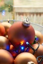 A glass bowl of mat bronze colored chtristmas balls and christmas lights