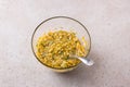 Glass bowl with mixed crushed pumpkin, eggs, sugar and oatmeal on a beige textured background. Cooking delicious