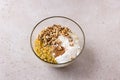 Glass bowl with mixed crushed pumpkin, eggs, sugar, oatmeal and flour, nuts and cinnamon on a beige textured background