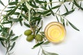 Glass bowl with olive oil, olives and branches with leafs. Close-up, top view with white background