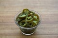 Glass bowl of pickled green jalapeno peppers on wooden table, closeup Royalty Free Stock Photo