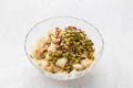 A glass bowl with pieces of puff pastry and nuts: hazelnuts, almonds and pistachios for a delicious arabic umm ali Royalty Free Stock Photo