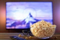 A glass bowl of popcorn, 3d glasses and remote control in the background the TV works. Evening cozy watching a movie or Royalty Free Stock Photo