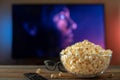 A glass bowl of popcorn, 3d glasses and remote control in the background the TV works. Evening cozy watching a movie or TV series Royalty Free Stock Photo