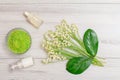 Bowl with sea salt, bottles with cream for face skin and aromatic oil, green leaves and bouquet of lilies of the valley Royalty Free Stock Photo