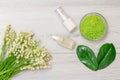 Glass bowl with sea salt, bottles with cream for face skin and aromatic oil, green leaves and bouquet of lilies of the valley Royalty Free Stock Photo