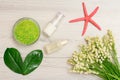 Glass bowl with sea salt, bottles with cream for face skin and aromatic oil, green leaves and bouquet of lilies of the valley