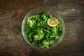 some green salad of spanac, lettuce, dill, arugula, parsley and a piece of lemon on the top on the wooden table