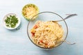 Glass bowl with summer pasta: spaghetti, tomatoes, red bell peppers, parsley, spices and grated cheese on a light blue Royalty Free Stock Photo