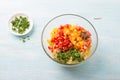 Glass bowl with summer pasta: spaghetti, tomatoes, red bell peppers, parsley and spices on a light blue background