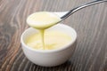 Bowl with sweet condensed milk, spoon with milk above bowl Royalty Free Stock Photo