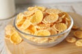 Glass bowl of tasty crispy corn flakes on wooden board, closeup Royalty Free Stock Photo