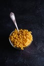 Glass bowl and vintage spoon with cavatappi uncooked golden wheat curly pasta on textured dark black background