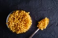 Glass bowl and vintage spoon with cavatappi uncooked golden wheat curly pasta on textured dark black background