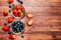 A glass bowls with strawberries and blueberries on a wooden table. Royalty Free Stock Photo