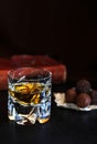 Glass of brandy with blurry red old book and chocolat at dark background
