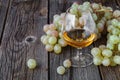 Glass of brandy with brush of grapes on table, harvest holiday Royalty Free Stock Photo