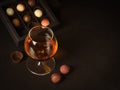 A glass of brandy and chocolate candy on a dark background. Alcoholic drink and elite chocolate food concept. Royalty Free Stock Photo