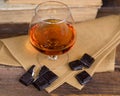 Glass of brandy and a chocolate on wooden table with books Royalty Free Stock Photo