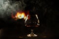 A glass of brandy and cigar smoke in the dark on the background of the fireplace. Gentlemen`s club concept Royalty Free Stock Photo